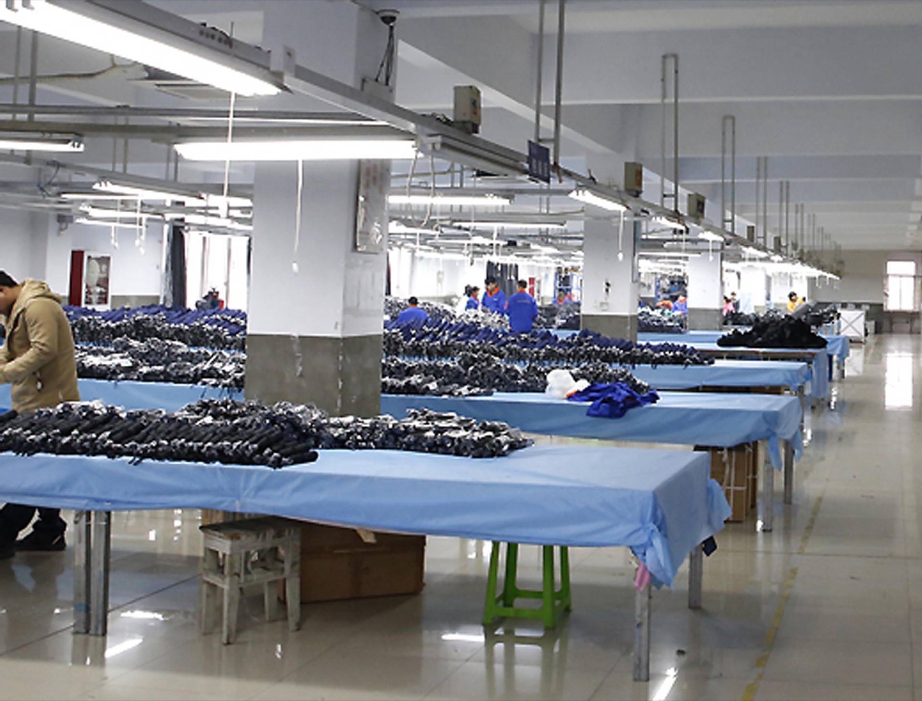 Assembly line with workers sorting folded umbrellas at long tables